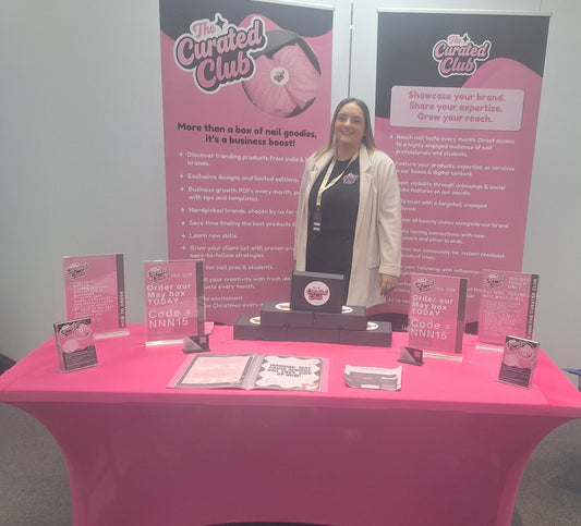 The Curated Club exhibition stand at Niche Nail Network 2026 with branded banners and nail tech business resources